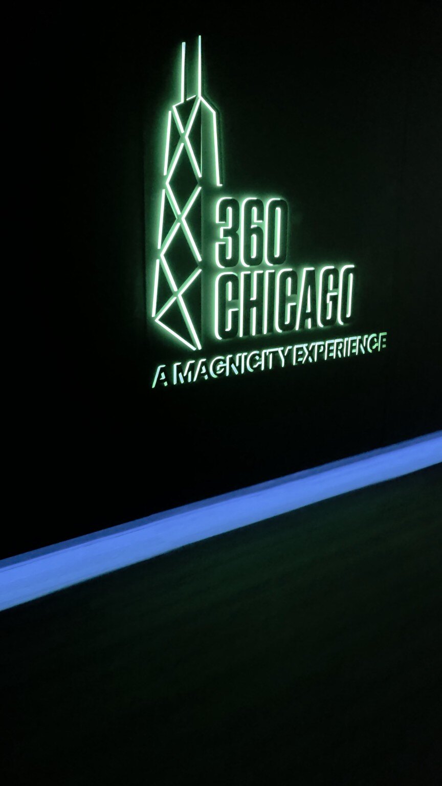 Green illuminated 360 CHICAGO sign inside the observation deck experience